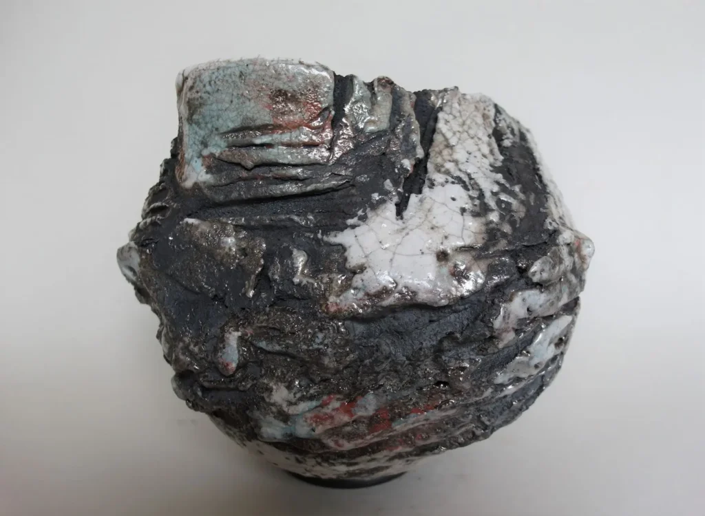 Gefäß Unikat, in Wulst Technik aus grobschamottierten Ton aufgebaut, Oberfläche strukturiert, teilweise glasiert, im Raku-Ofen gebrannt und in Sägespänen abgeräuchert.